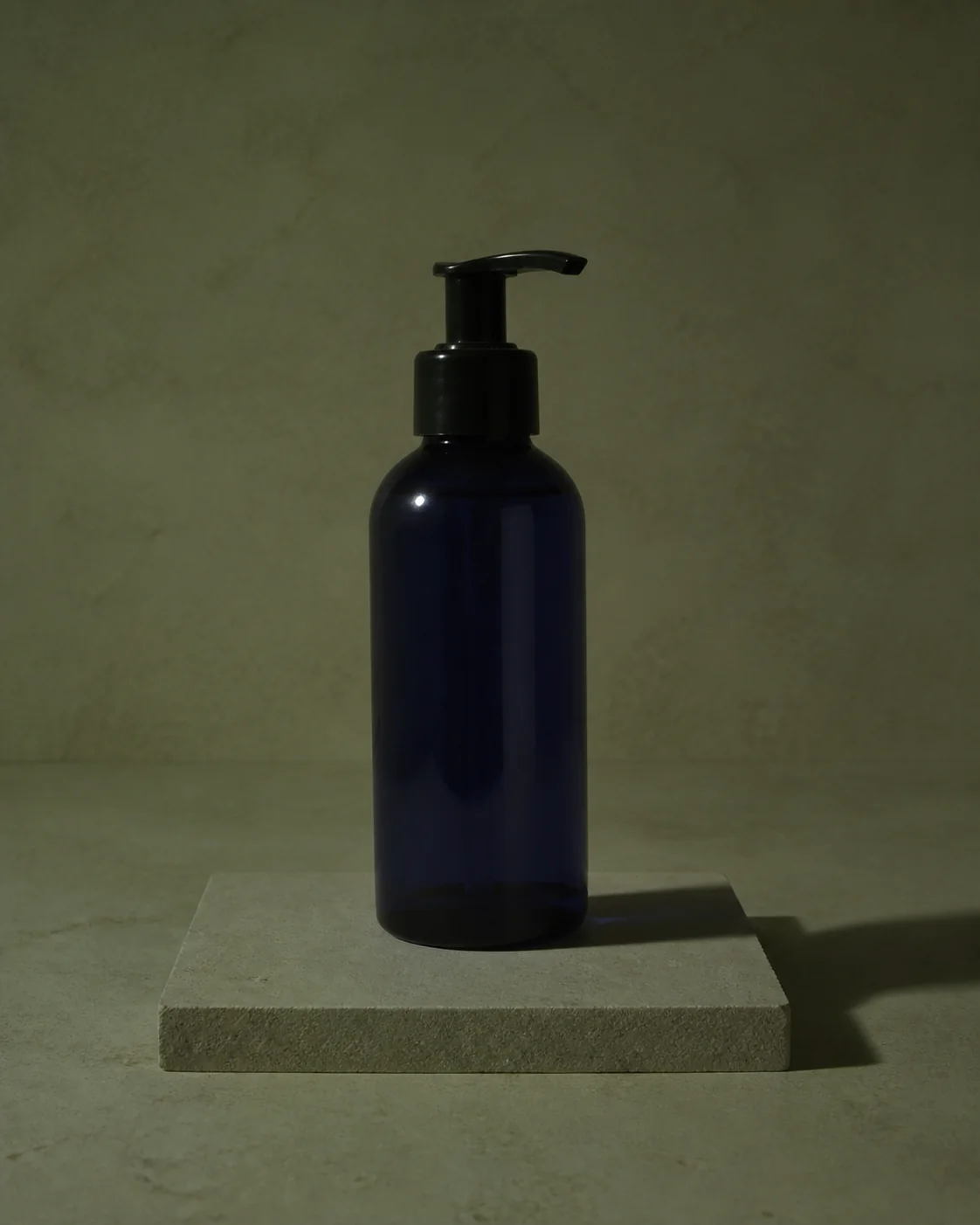 Underexposed blue skincare bottle with a green cast and hard shadow.