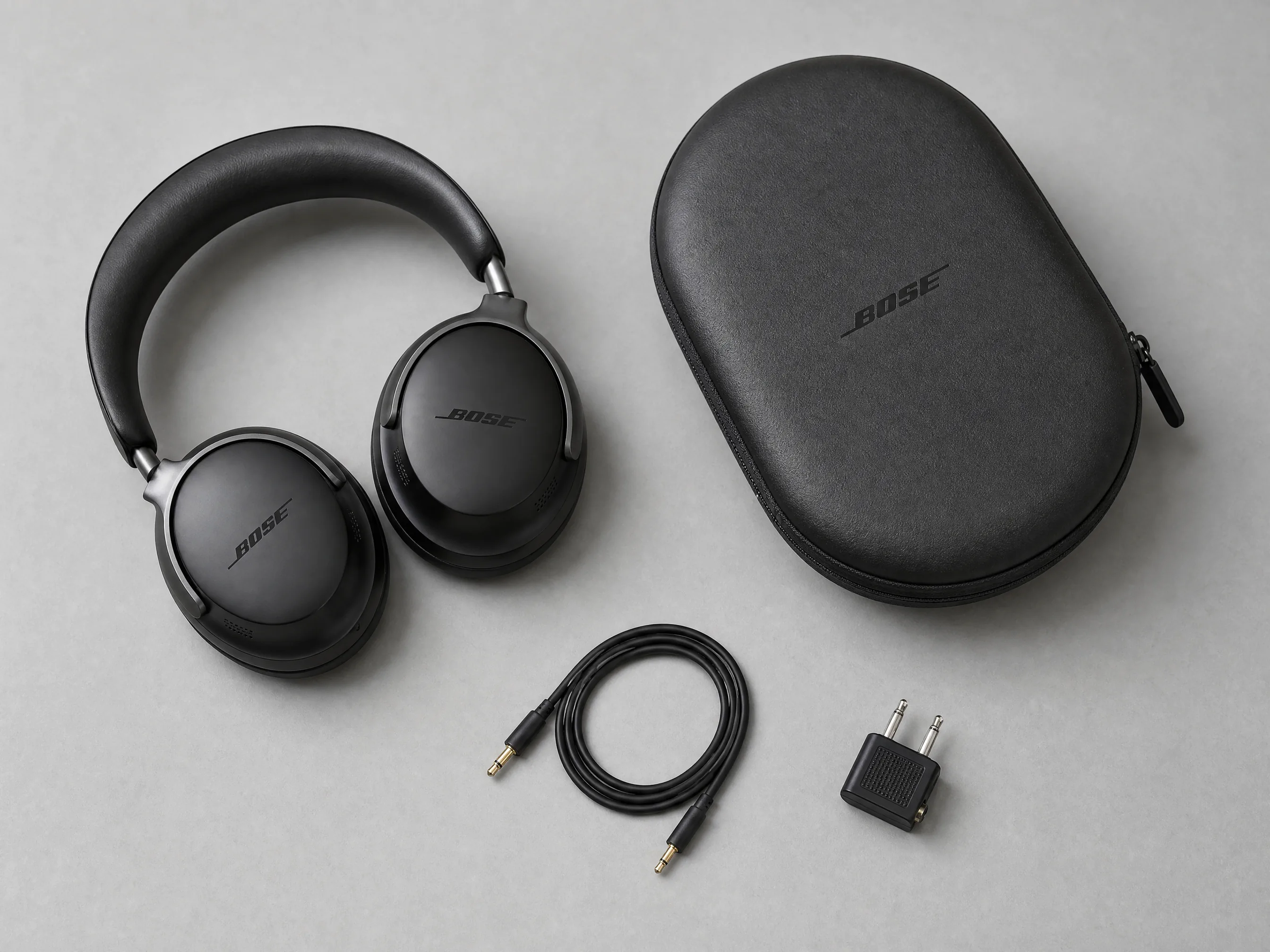 Black over-ear headphones, their case, and cable arranged in a clean top-down composition.